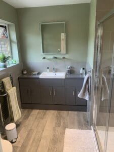 After picture of a bathroom tiled with large grey tiles and wood effect porcelain plank flooring in Warlingham
