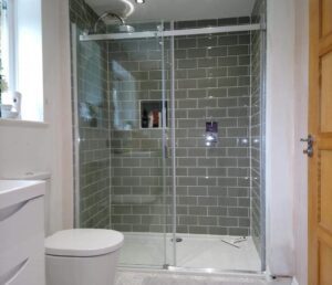 Bathroom with a large shower room with sage green metro tiles and a tiled niche