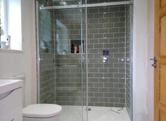 Bathroom with a large shower room with sage green metro tiles and a tiled niche