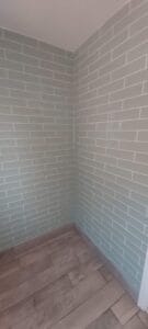 Bathroom corner comprising of long mint green metro tiles on wall and wood effect porcelain planks on floor