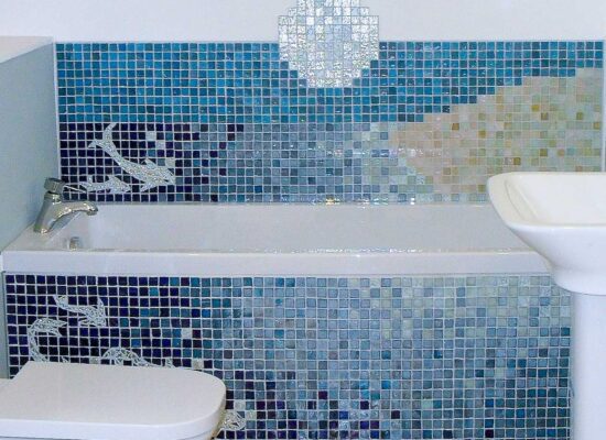 blue mosaic tiles in an ocean design on the wall around a white bath and also bath panel